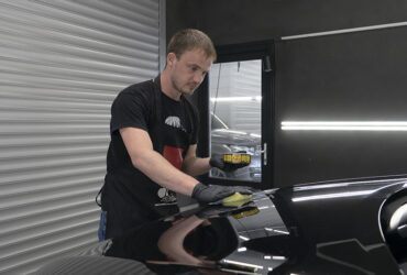 студент учится наносить защитный воск на кузов